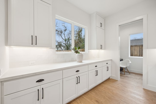 interior space with backsplash, light hardwood / wood-style flooring, and white cabinets