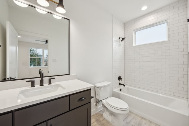 full bathroom with tiled shower / bath, vanity, toilet, and wood-type flooring