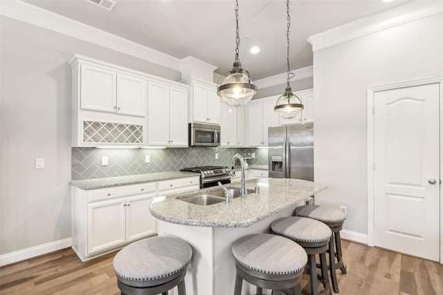 kitchen featuring pendant lighting, sink, a kitchen island with sink, stainless steel appliances, and white cabinets