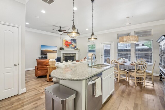 kitchen featuring sink, a center island with sink, stainless steel dishwasher, pendant lighting, and white cabinets