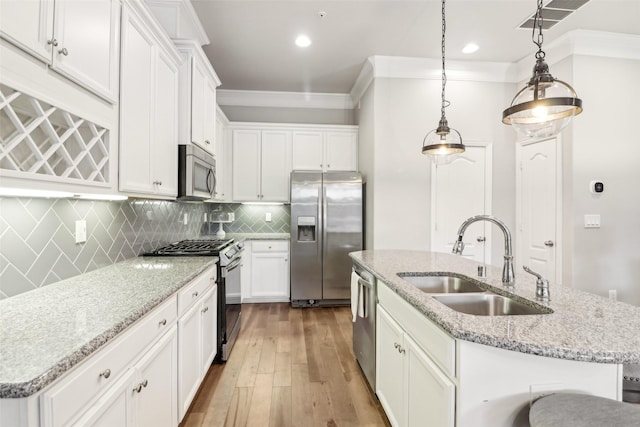 kitchen with sink, white cabinets, hanging light fixtures, a kitchen island with sink, and stainless steel appliances