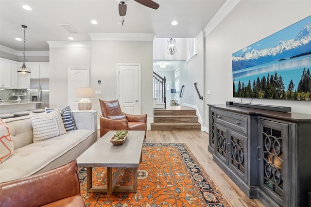 living room featuring ceiling fan, ornamental molding, and light hardwood / wood-style floors