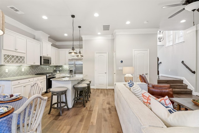 kitchen featuring appliances with stainless steel finishes, a breakfast bar, an island with sink, and white cabinets