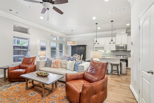 living room featuring crown molding, light hardwood / wood-style flooring, and ceiling fan