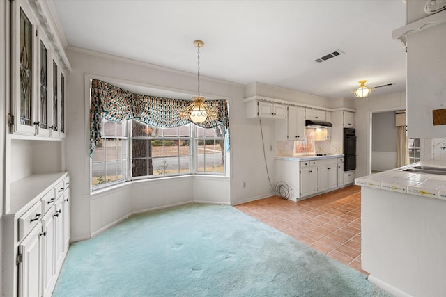 kitchen featuring hanging light fixtures, tasteful backsplash, tile counters, and white cabinets