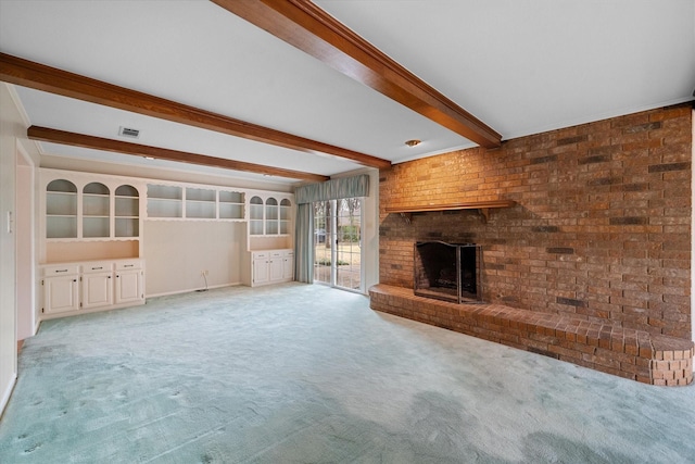 unfurnished living room featuring a brick fireplace, beam ceiling, and light colored carpet