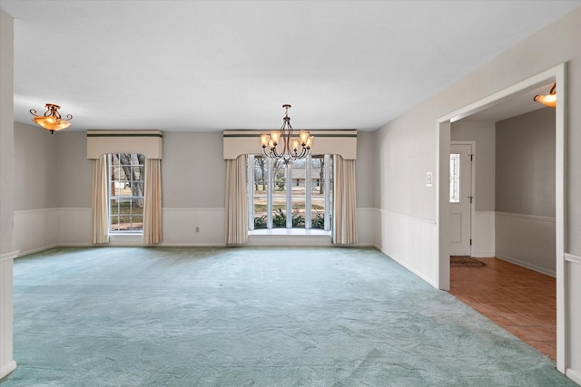 empty room with an inviting chandelier and light colored carpet