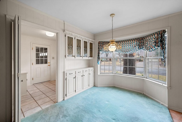 unfurnished dining area featuring crown molding and light colored carpet