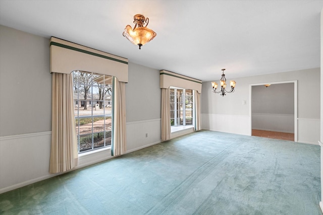 spare room with plenty of natural light, carpet flooring, and an inviting chandelier