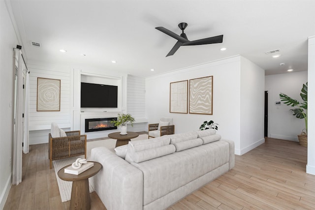 living room featuring crown molding, ceiling fan, and light hardwood / wood-style floors