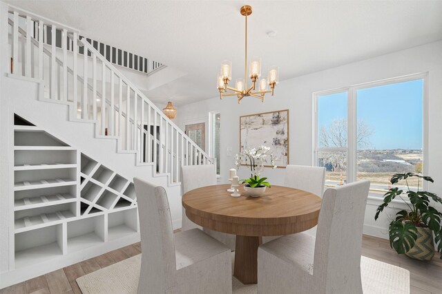 dining room with built in shelves, a chandelier, and light wood-type flooring