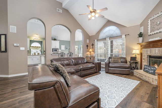 living room with dark hardwood / wood-style floors, high vaulted ceiling, sink, ceiling fan, and a brick fireplace