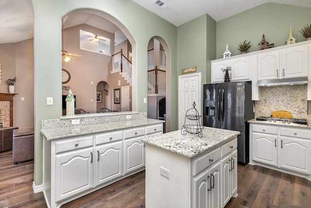 kitchen with light stone counters, appliances with stainless steel finishes, kitchen peninsula, a kitchen island, and white cabinets