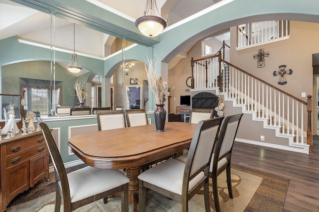 dining area featuring a towering ceiling and wood-type flooring