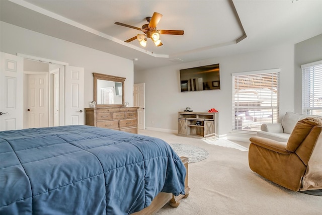 bedroom with a raised ceiling, carpet flooring, and ceiling fan