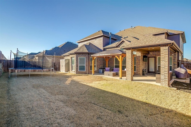 back of house featuring a patio area, a trampoline, and a lawn