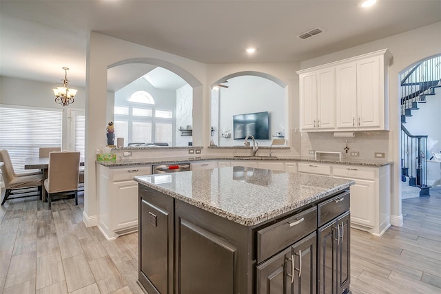 kitchen with dark brown cabinetry, tasteful backsplash, light hardwood / wood-style flooring, a kitchen island, and white cabinets