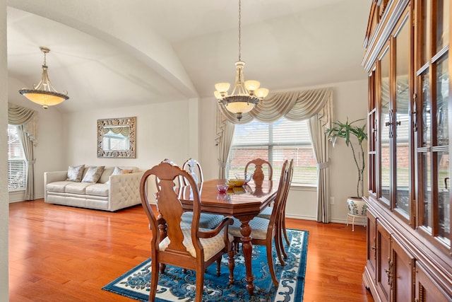 dining area with lofted ceiling, a chandelier, and light wood-type flooring