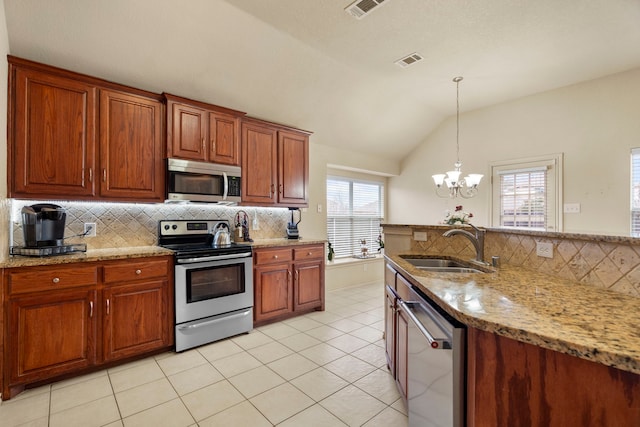 kitchen with pendant lighting, sink, stainless steel appliances, light stone countertops, and vaulted ceiling