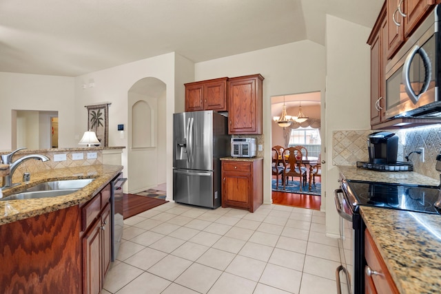 kitchen featuring sink, appliances with stainless steel finishes, light stone counters, light tile patterned flooring, and decorative backsplash