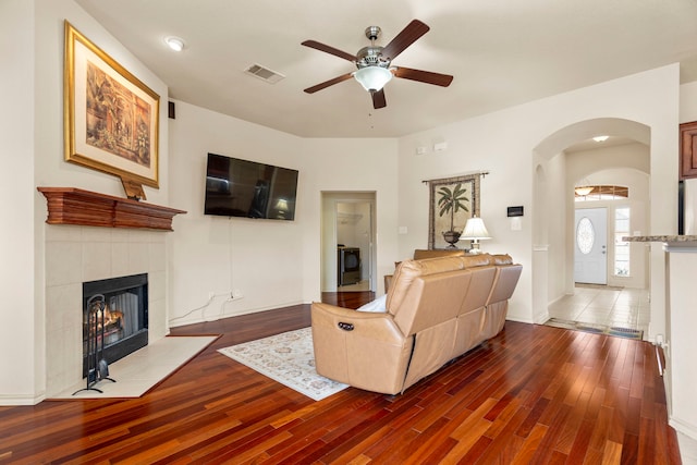 living room featuring hardwood / wood-style flooring, ceiling fan, and a fireplace