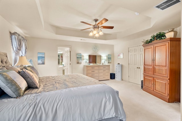 carpeted bedroom featuring connected bathroom, ceiling fan, and a tray ceiling