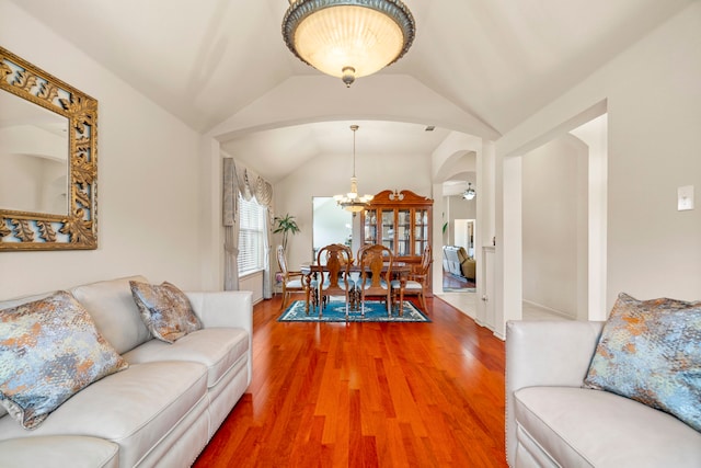 living room with lofted ceiling, a notable chandelier, and wood-type flooring