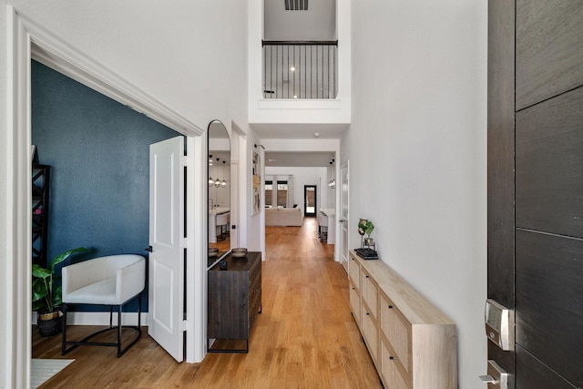 hall featuring a high ceiling and light wood-type flooring