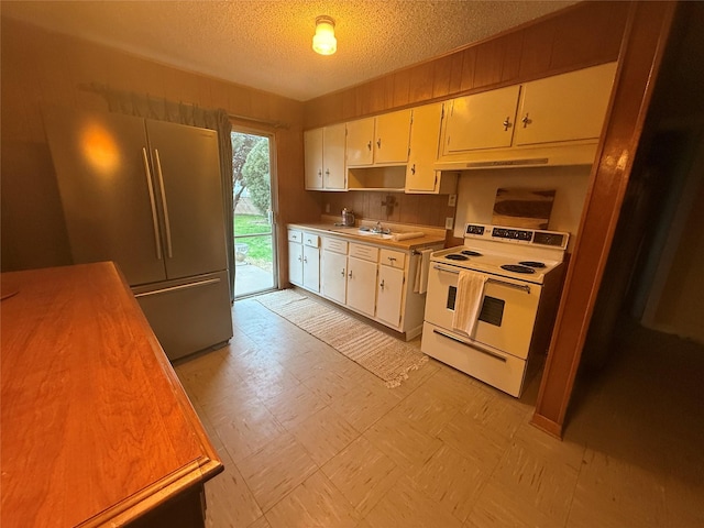 kitchen featuring stainless steel refrigerator, white cabinetry, sink, white range with electric cooktop, and a textured ceiling