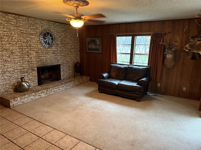 unfurnished living room featuring a fireplace, wood walls, carpet floors, ceiling fan, and a textured ceiling