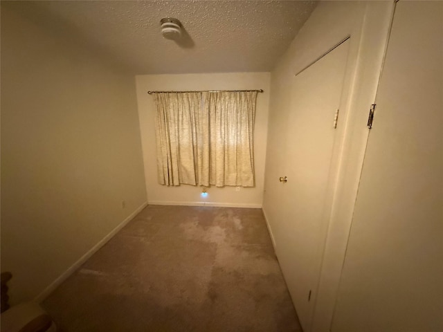 unfurnished bedroom with a textured ceiling and dark colored carpet