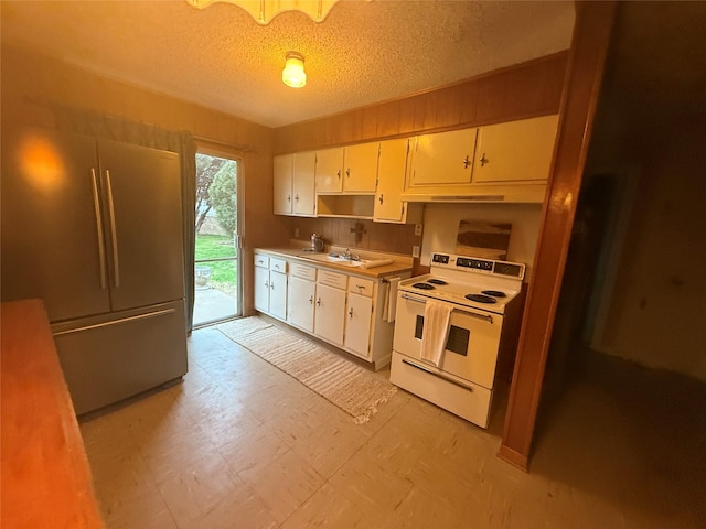 kitchen featuring sink, refrigerator, a textured ceiling, electric stove, and white cabinets