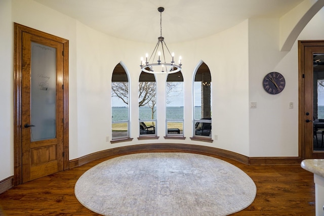 dining room with a water view, dark wood-type flooring, and a notable chandelier