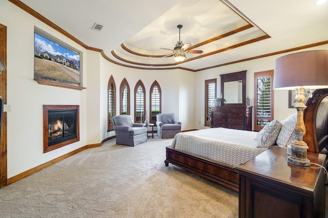 bedroom featuring multiple windows, a tray ceiling, light carpet, and ornamental molding