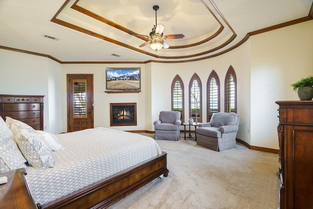 bedroom with multiple windows, a tray ceiling, and light colored carpet