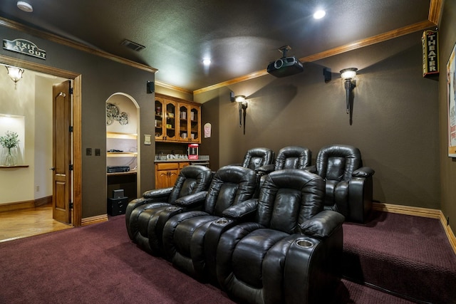 carpeted cinema room with ornamental molding and a textured ceiling