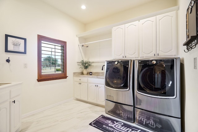 clothes washing area featuring cabinets, sink, and washer and clothes dryer