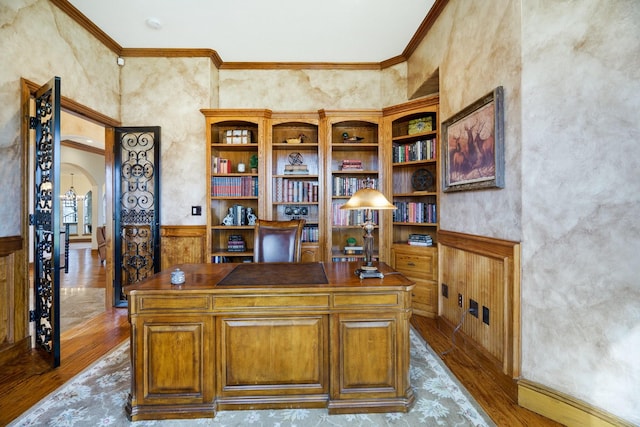 home office featuring a towering ceiling, ornamental molding, and light hardwood / wood-style floors