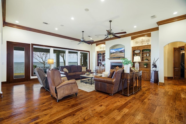 living room with ornamental molding, dark hardwood / wood-style floors, ceiling fan, and built in shelves