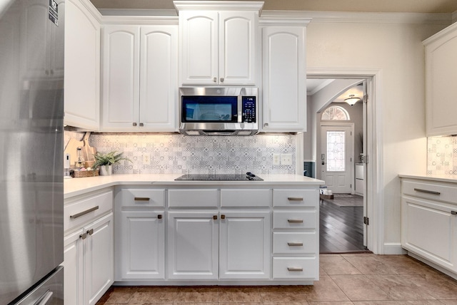 kitchen featuring white cabinetry, ornamental molding, stainless steel appliances, and tasteful backsplash