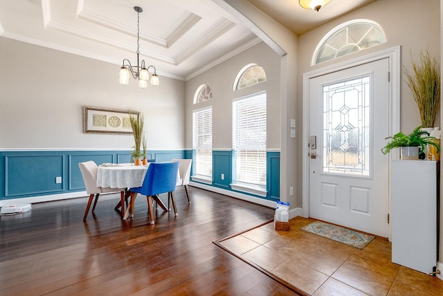 entrance foyer featuring a chandelier, ornamental molding, a tray ceiling, and dark hardwood / wood-style flooring