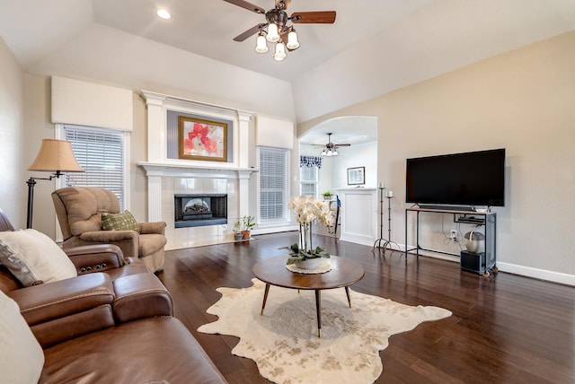 living room featuring dark wood-type flooring, a fireplace, ceiling fan, and vaulted ceiling