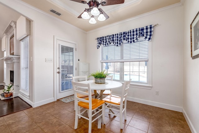 tiled dining space with ceiling fan and ornamental molding