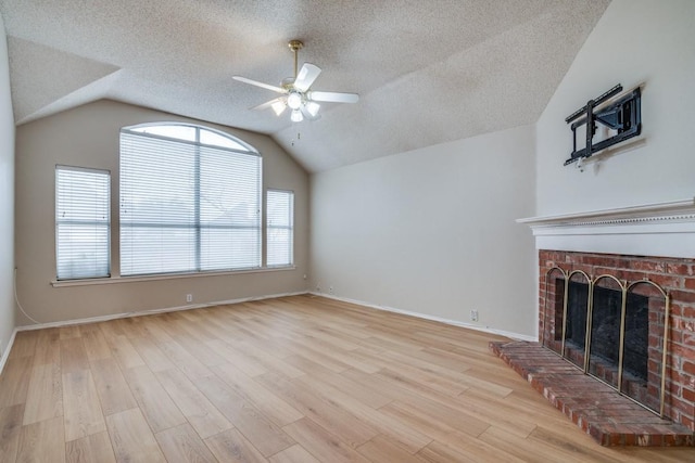 unfurnished living room featuring a fireplace, light hardwood / wood-style floors, ceiling fan, and vaulted ceiling