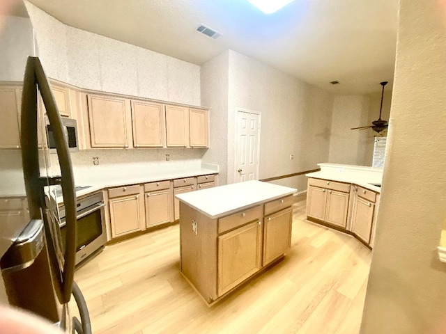 kitchen featuring appliances with stainless steel finishes, a kitchen island, light brown cabinetry, ceiling fan, and light hardwood / wood-style floors