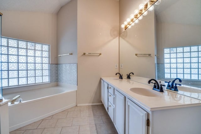 bathroom featuring tile patterned floors, a bathing tub, vaulted ceiling, and vanity