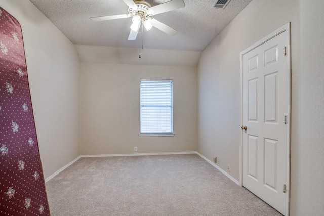 carpeted empty room with ceiling fan, vaulted ceiling, and a textured ceiling