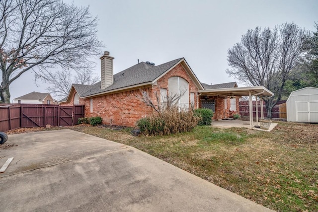 rear view of house featuring a yard, a storage unit, and a patio