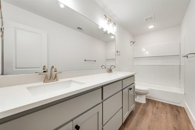 full bathroom with wood-type flooring, vanity, washtub / shower combination, and toilet