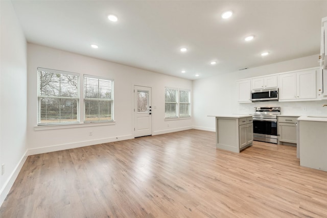 kitchen with sink, stainless steel appliances, white cabinets, and light wood-type flooring